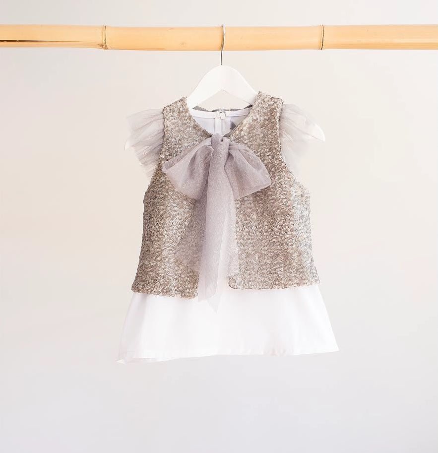 Dress your girl with style with this basic white T-shirt with silver frills in the sides! It will make any outfit to stand out. A sweet and girly design.